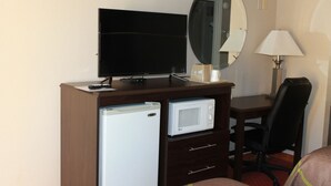 A hotel room with a flat-screen TV, a microwave, a refrigerator, a desk, a chair, and a bedside lamp. - Super 8 by Wyndham Locust Grove (Locust Grove)