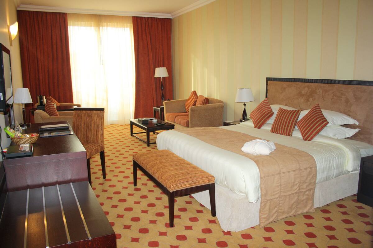 Une chambre d’hôtel avec un grand lit, un bureau, une chaise et un canapé.