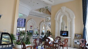 A spacious lobby with high ceilings, arched columns, and a television screen. - Grand Continental Hotel (Abu Dhabi)