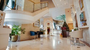 A spacious lobby with a high ceiling, a staircase, and a reception desk. - Grand Continental Hotel (Abu Dhabi)