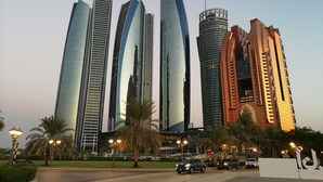 A modern hotel with a distinctive curved facade, multiple floors, and a prominent entrance with a sign. - Grand Continental Hotel (Abu Dhabi)