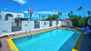 A swimming pool with lounge chairs, a flag, and a building with a '6' sign. - Motel 6 Tucson, AZ - East Williams Center (Tucson)