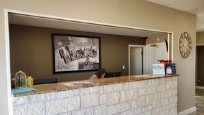 A reception desk with a framed welcome sign, a clock, and a door in the background.