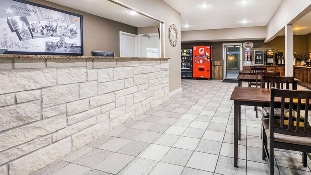 A reception area with a stone wall, a clock, and a vending machine.