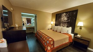 A hotel room with a large bed, bedside lamps, a desk, and a mirror.