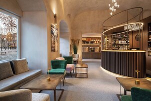 Un'area lounge moderna con posti a sedere, un bar e una cucina sullo sfondo.