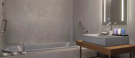 A modern bathroom with a bathtub, a vanity with a mirror, and a shelf with towels.