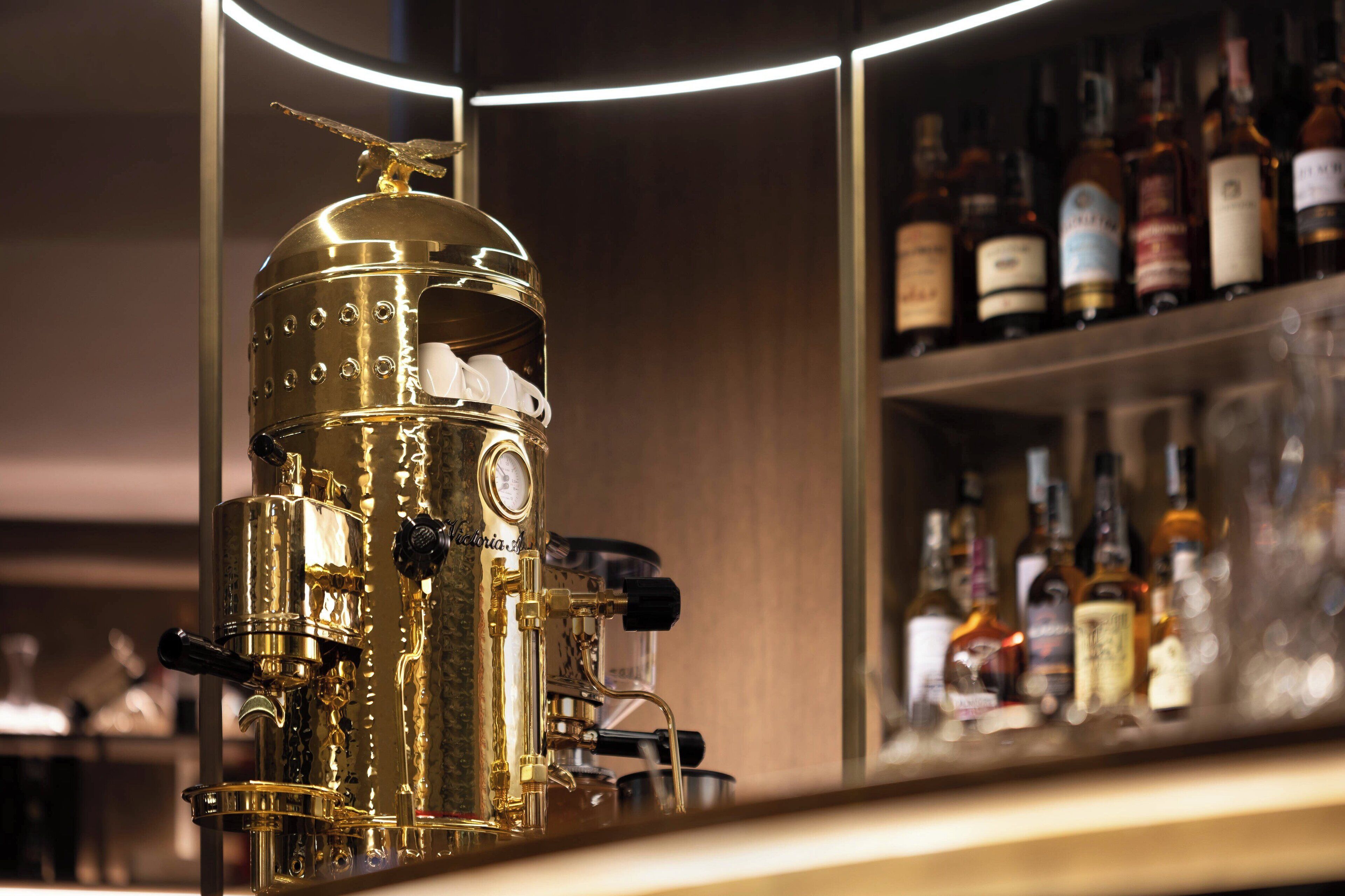 A bar with a vintage espresso machine and shelves of liquor bottles.
