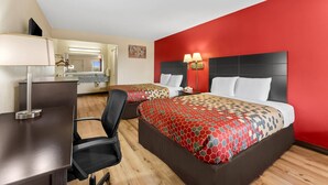 Quarto de hotel com duas camas, uma escrivaninha e uma cadeira.