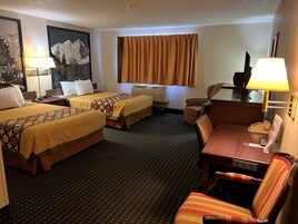 Habitación de hotel con dos camas, un escritorio, una silla, un televisor, una lámpara y un cuadro en la pared.