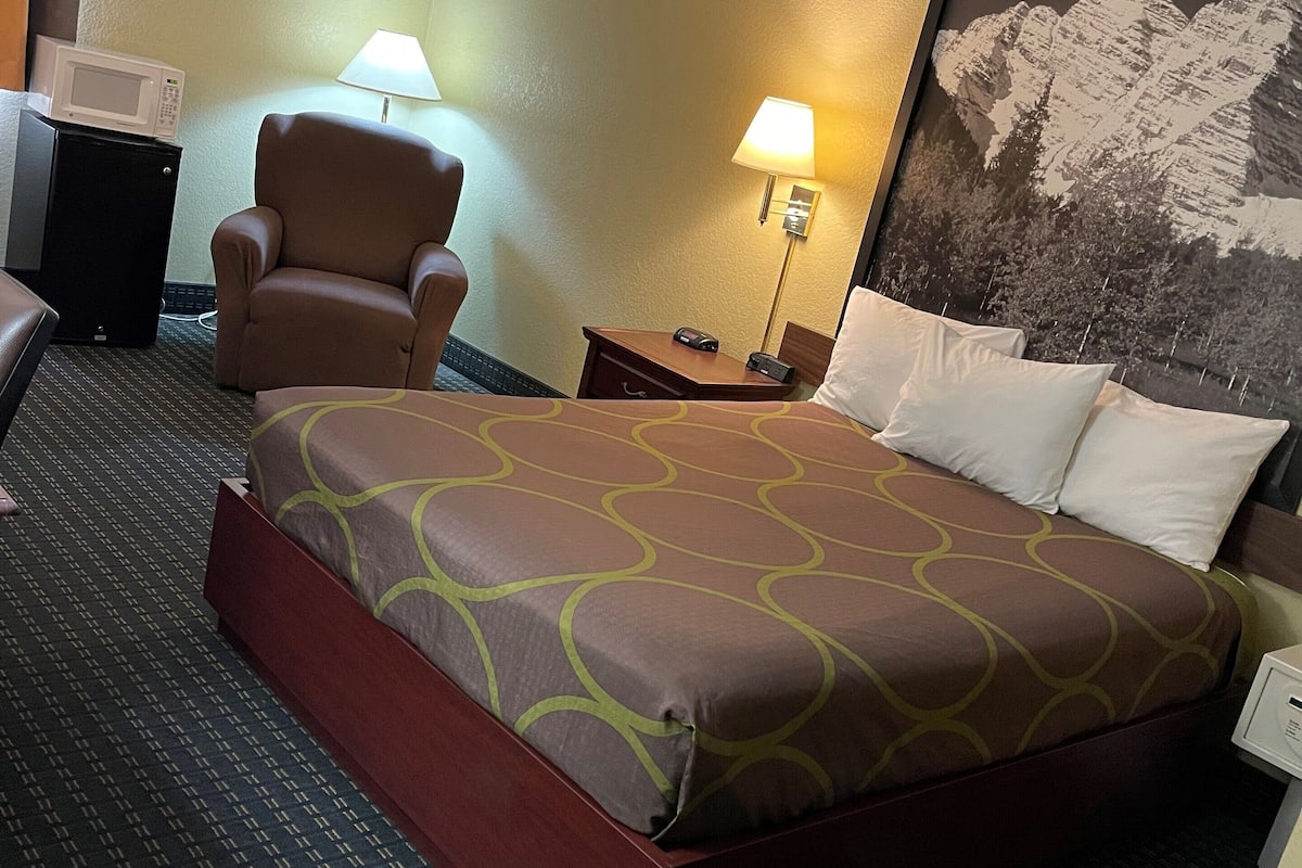 Une chambre d’hôtel avec un grand lit, une chaise, un bureau et une lampe.