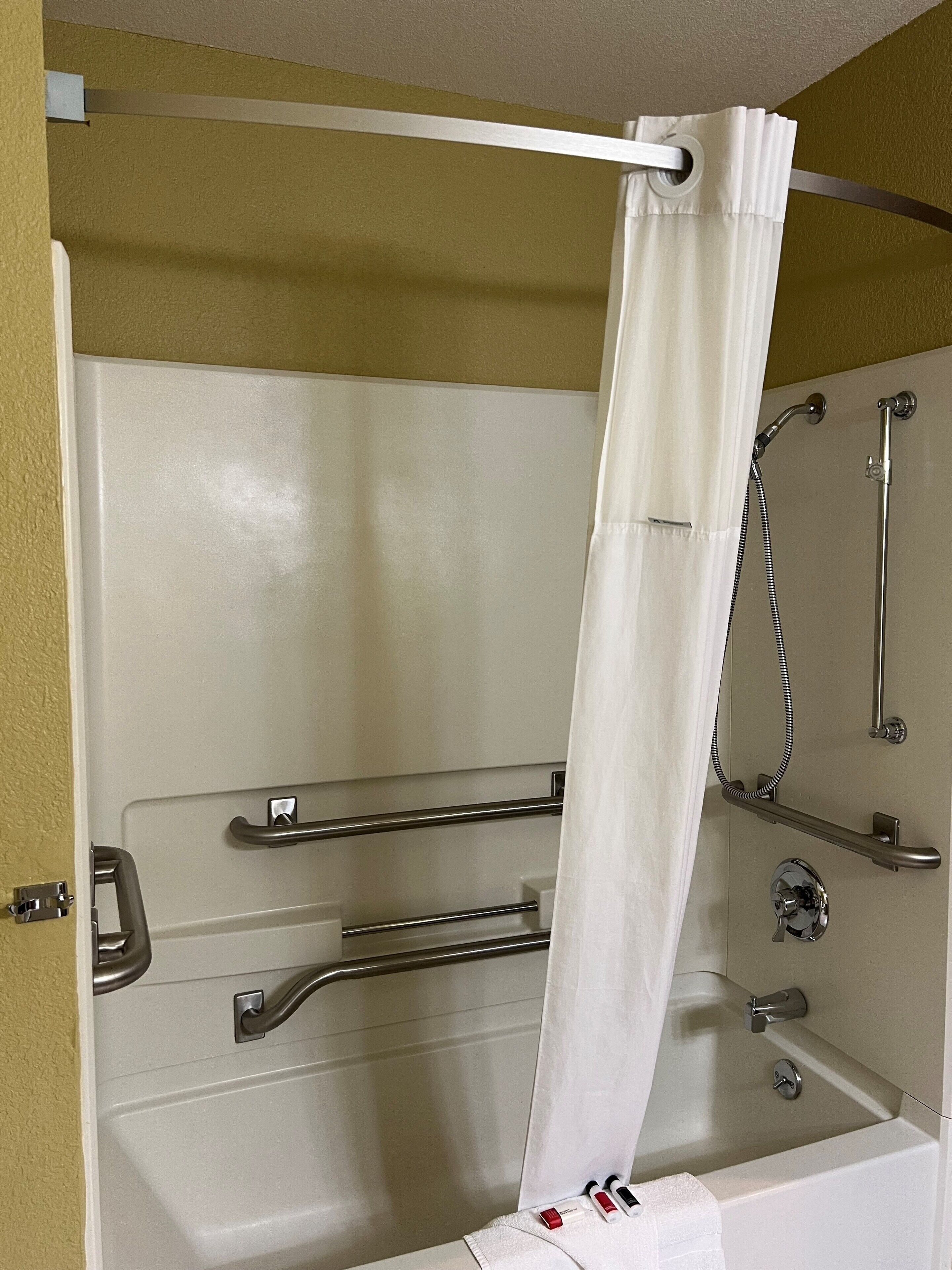 A walk-in shower with a glass door, grab bars, a showerhead, and a towel rack.