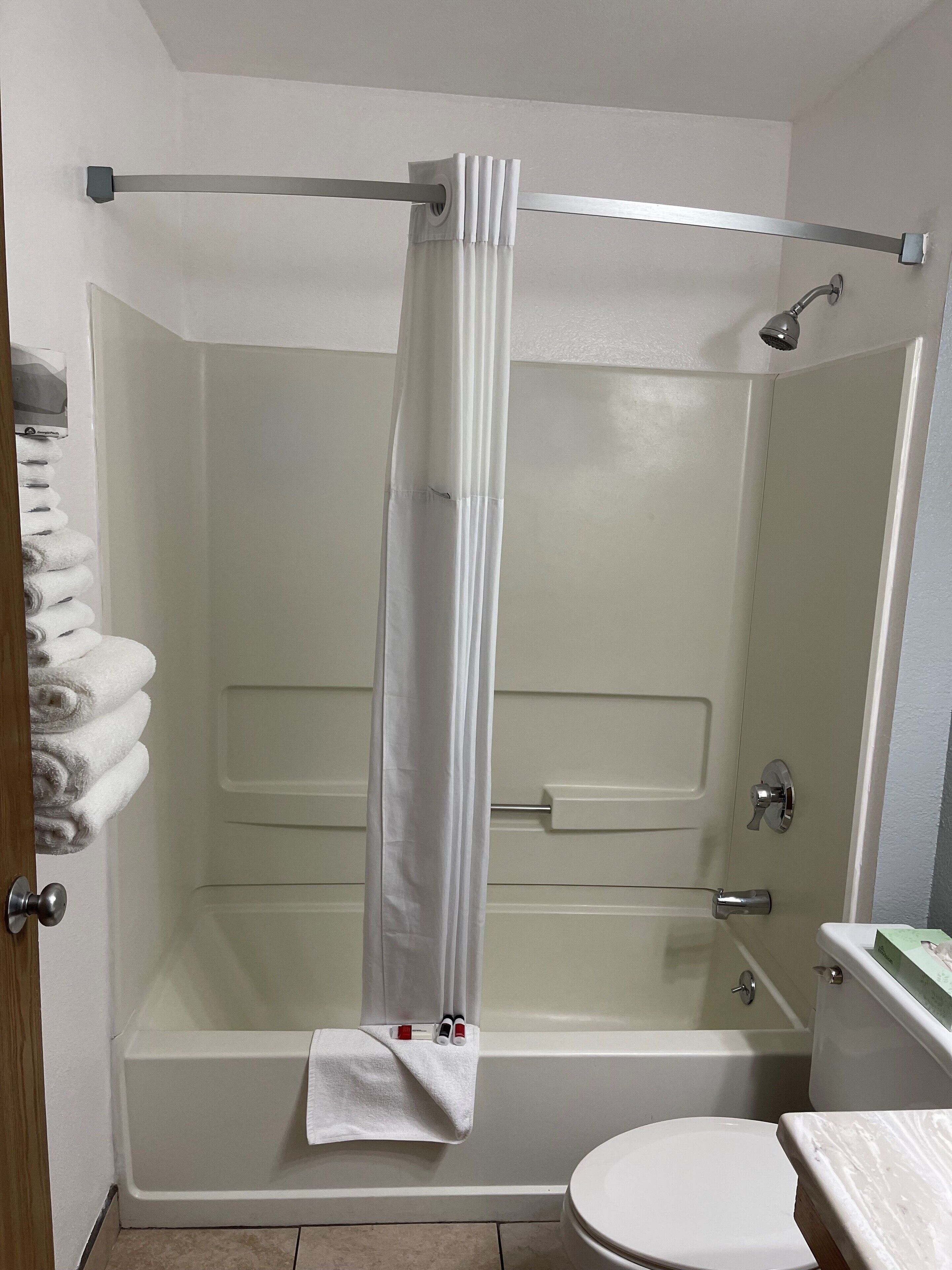 A bathroom with a bathtub, toilet, and shower curtain.