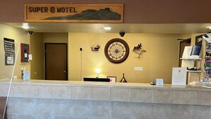 Un comptoir d’accueil dans le motel Super 8, avec une enseigne en bois au-dessus, une horloge et des décorations en forme de bois de cerf sur le mur.