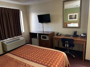 Relax in comfort with a neatly made bed, a desk with a flat-screen TV, telephone, and coffee maker, and a large mirror.