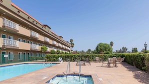 A swimming pool with a hot tub, outdoor seating, and a multi-story building with balconies. - Travelodge by Wyndham Sylmar CA (Sylmar)