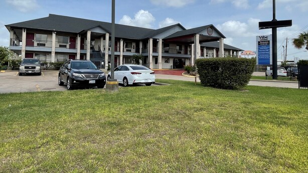 A multi-story motel with a central entrance and a parking lot. - Americas Best Value Inn Houston Hobby Airport (Houston)