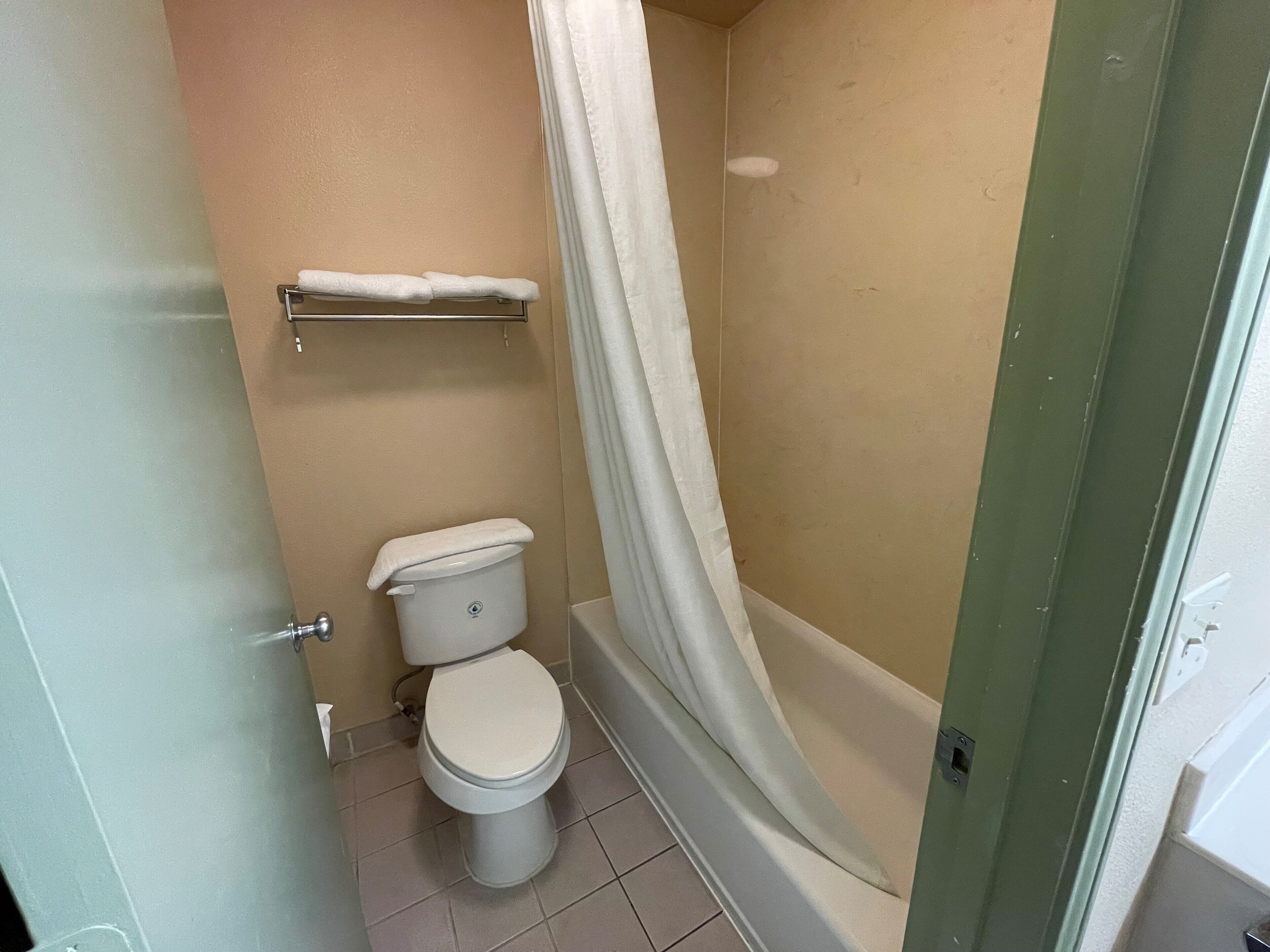 A bathroom with a toilet, a shower curtain, and a towel rack.