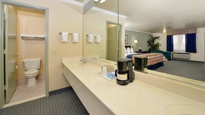 A hotel bathroom with a toilet, sink, and large mirror. - Americas Best Value Inn Houston Hobby Airport (Houston)