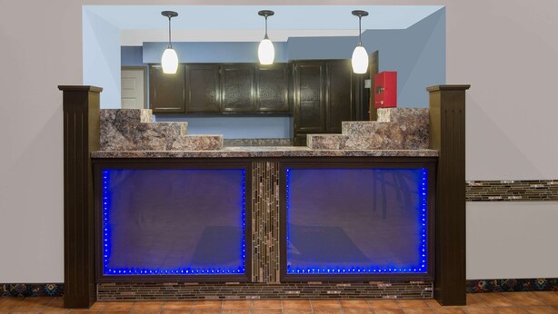 Una cocina con armarios de madera oscura, encimera de granito e iluminación LED azul.
