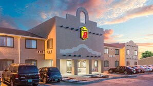 Un hotel con un letrero Super 8, varios espacios de estacionamiento y un diseño arquitectónico moderno.