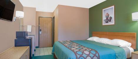 A hotel room with a bed, a television, a desk, and a door leading to another room.
