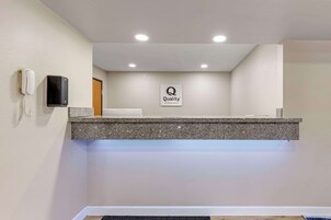 Una zona de recepción con mostrador de granito, un letrero que dice 'Quality', un teléfono y una puerta.