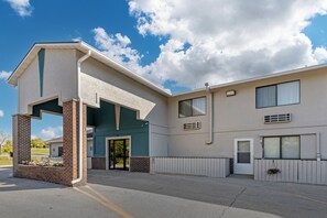 A two-story building with a covered entrance, a brick column, and a small garden area with flowers. - Quality Inn Indianola (Indianola)