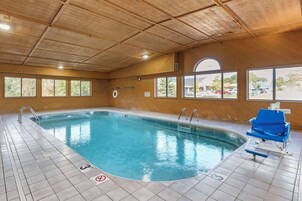 Una piscina interior con suelo de baldosas, agua cristalina y una silla azul junto a la piscina.