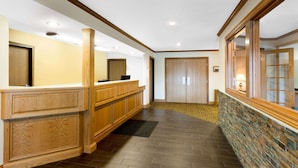 Un área de recepción con un mostrador de madera, una pared decorativa de piedra y piso alfombrado.