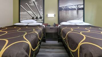 Habitación de hotel con dos camas, una mesita de noche y una lámpara fijada a la pared.