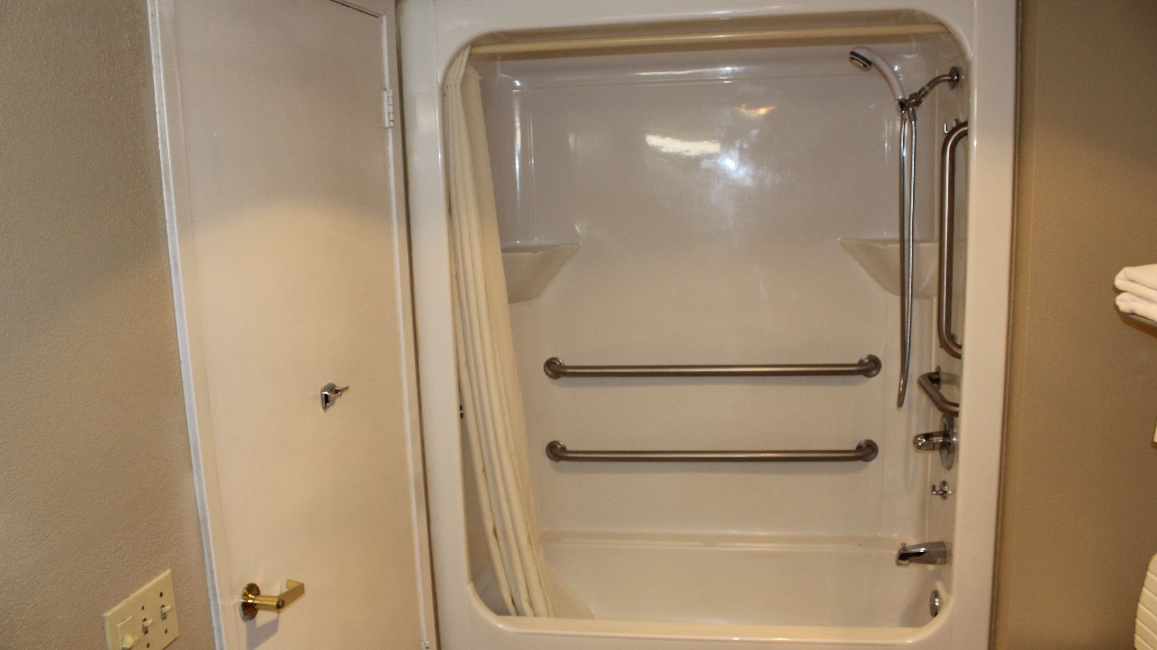 Un baño con bañera, ducha y dos barras para toallas.