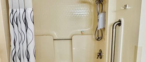 Una bañera con ducha, baranda y toalla.