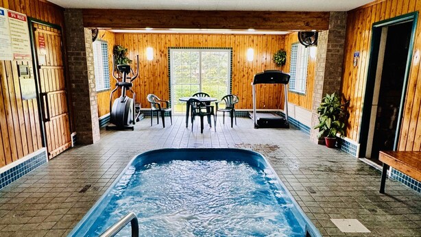 Ein Innenpool mit einem 3 Fuß hohen Sprungbrett, Holzwänden und einer Sitzecke mit Stühlen und einem Tisch.
