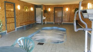 Ein Holzinnenraum mit Whirlpool, einer Sitzbank und einer Bedienkonsole.