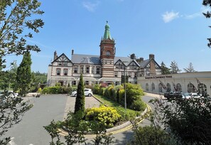 A historic building with a prominent tower, a parking lot, and a sign for a conference venue. - The Lucan Spa Hotel (Lucan)