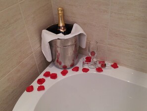 A bathtub with rose petals and a champagne bottle in a bucket. - The Lucan Spa Hotel (Lucan)