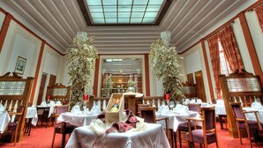 Un comedor formal con mesas dispuestas para una comida, un candelabro y un ventanal con vistas.