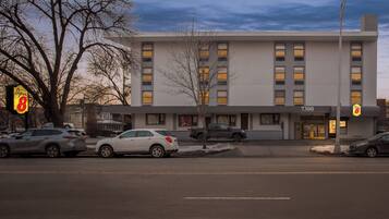 A modern building with a flat facade, multiple windows, and a parking lot with several cars.