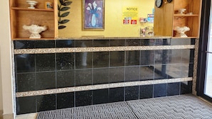 A reception area with a black tiled wall, a notice board, and decorative items including a vase and a plant.