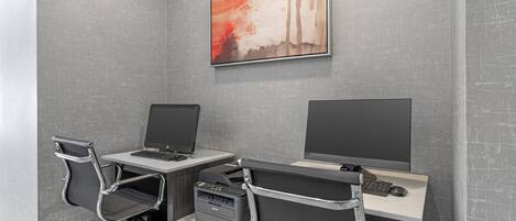 A modern office space with two desks, each with a computer and a printer.