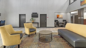 A modern lobby with a sofa, armchairs, a coffee table, and a desk area.