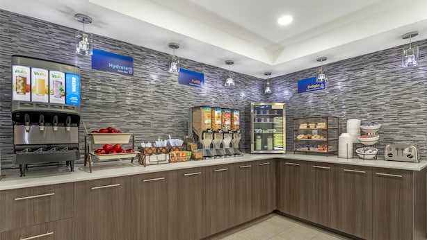 A modern breakfast bar with juice dispensers, a selection of cereals, and a variety of breakfast items.