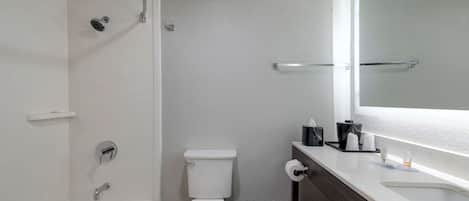 A modern bathroom with a bathtub, toilet, and a vanity with a mirror.