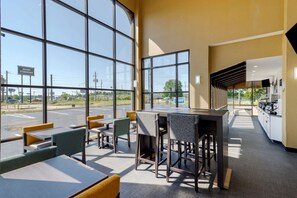 Un restaurante moderno con amplios ventanales, mesas al aire libre y una zona de cocina.