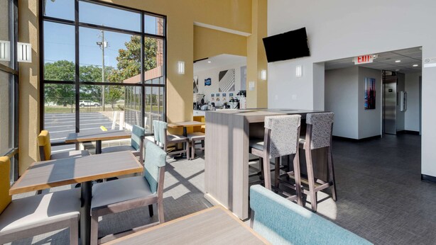 A modern interior with seating areas, a kitchen, and an exit sign. - Clarion Pointe McDonough (McDonough)