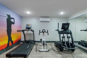 Un gimnasio con cintas de correr, elípticas y una bicicleta estática.