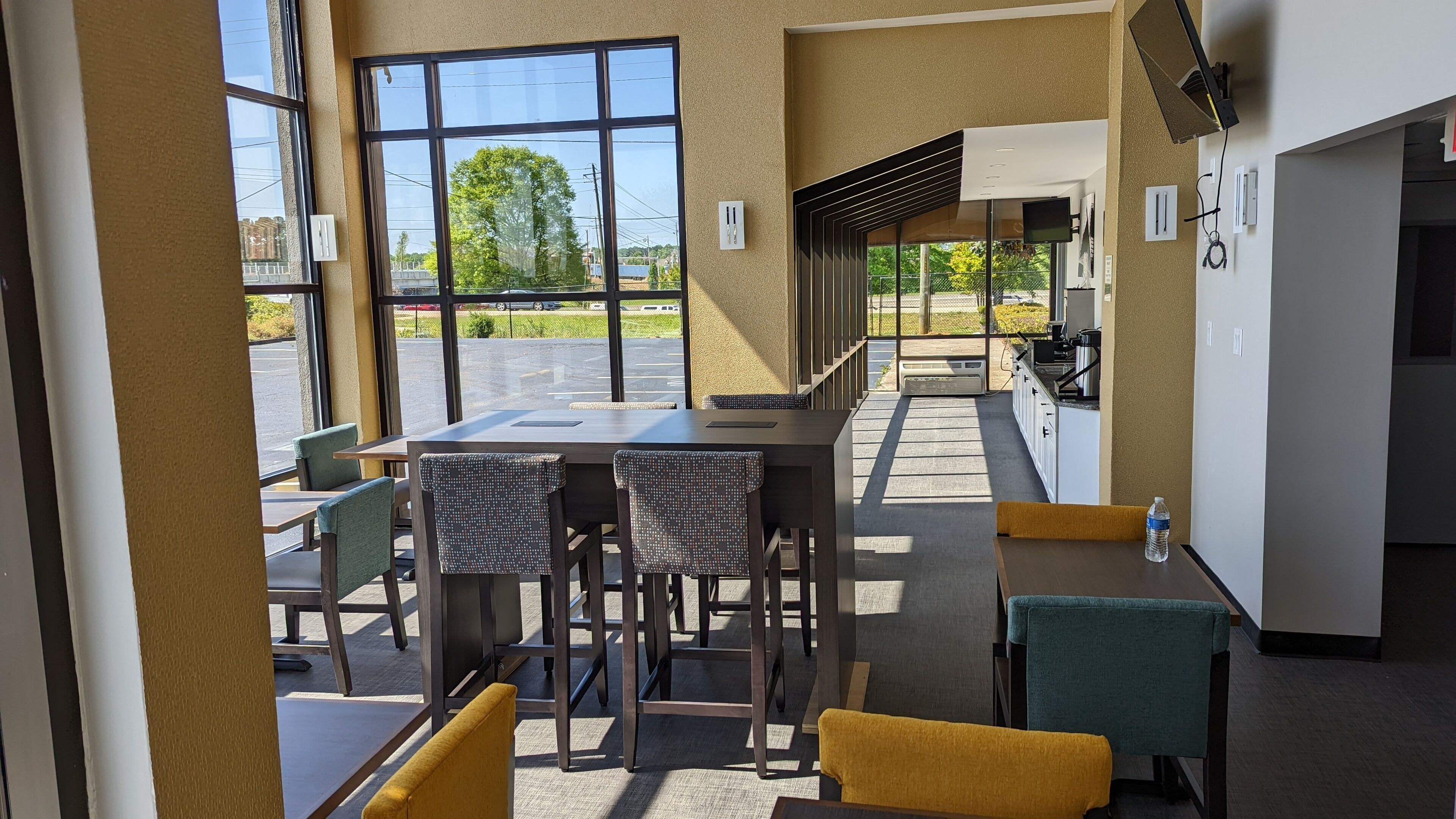 A modern indoor space with a long counter, seating area, and a view of the parking lot.