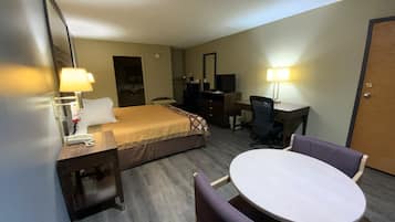 Una habitación de hotel con cama, escritorio, silla y una pequeña mesa redonda.