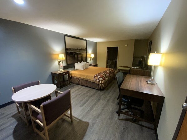 Habitación de hotel con cama, escritorio, silla y una mesa redonda.